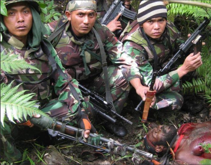 MIliter Indonesia dari Angkatan Darat sedang berpose di depan mayat orang Papua usai ditembak mati (Foto: IST/SP)